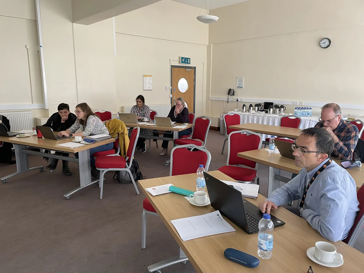 Researchers working at laptops around tables in a seminar room during one of Huw's courses.