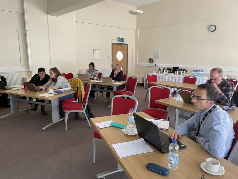 Researchers working at laptops around tables in a seminar room during one of Huw's courses.